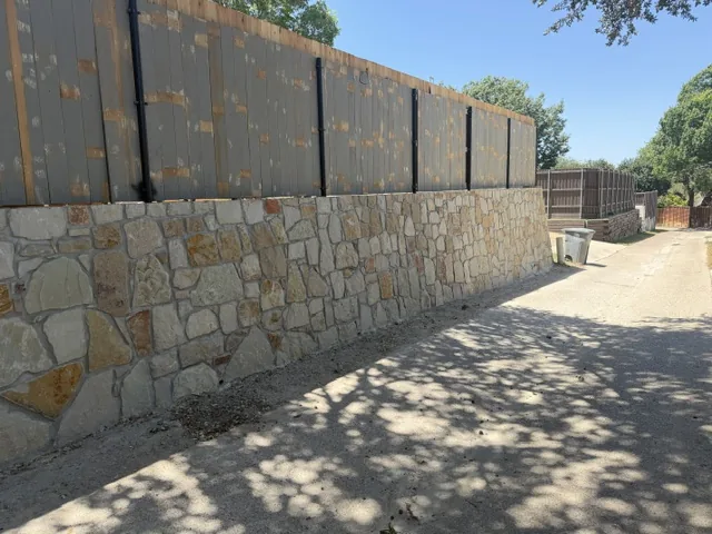Completed natural stone retaining wall running the length of a Dallas side yard