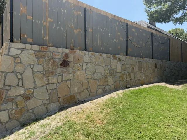 Natural stone retaining wall with tight joints holding back a lawn in Dallas Texas