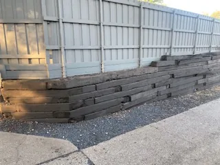 Close view of separating railroad ties and open joints in a failing Dallas retaining wall