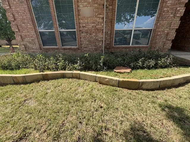 Curved Milsap stone border edging a flower bed along a brick house in Benbrook, TX