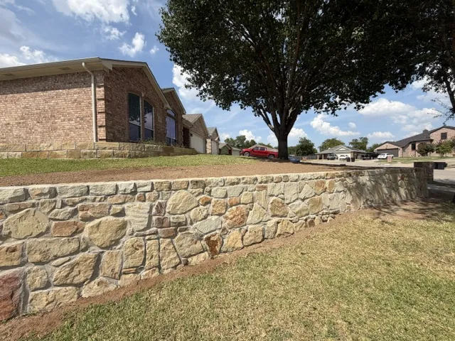 Existing stone retaining wall raised to a taller Milsap face in front of a brick home in Benbrook, TX