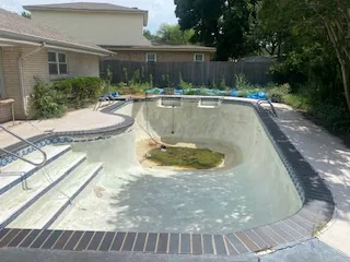 Drained in-ground pool showing the deep end, steps and ladder in North Richland Hills before demolition