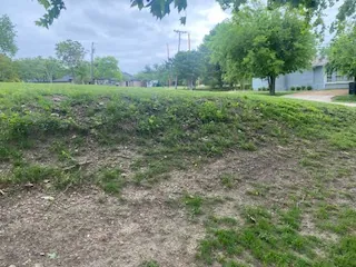 Patchy, eroding grass slope in a Prosper, TX yard before a Milsap stone retaining wall