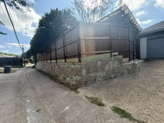 New natural Milsap stone retaining wall turning the corner beside an alley and garage in Dallas, TX