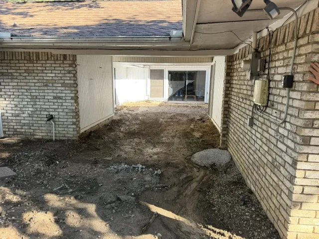 Courtyard graded level after pool removal — Lewisville TX Lewisville courtyard backfilled and graded level after partial pool and spa demolition, between the brick walls of the house